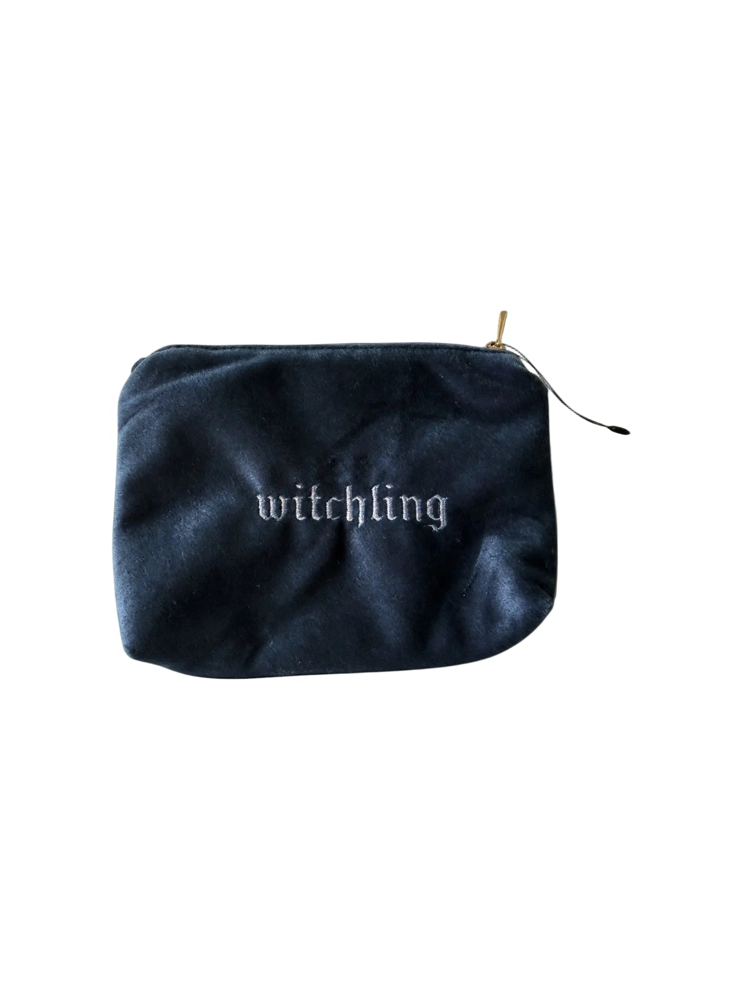 A dark navy blue velvet pouch with the word 'witchling' embroidered in white gothic lettering on the front, featuring a gold zipper pull, set against a solid white background.